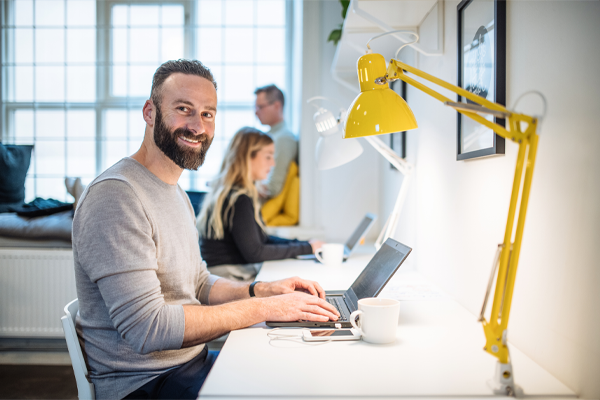 team working at desk with man looking at camera