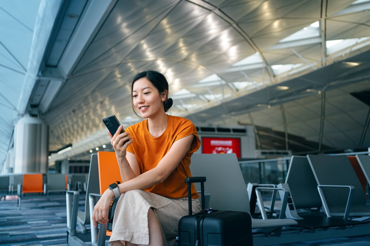 Geschäftsreisende nutzt die mobile SAP-Concur-App am Flughafen zur Reiseplanung und Abrechnung.
