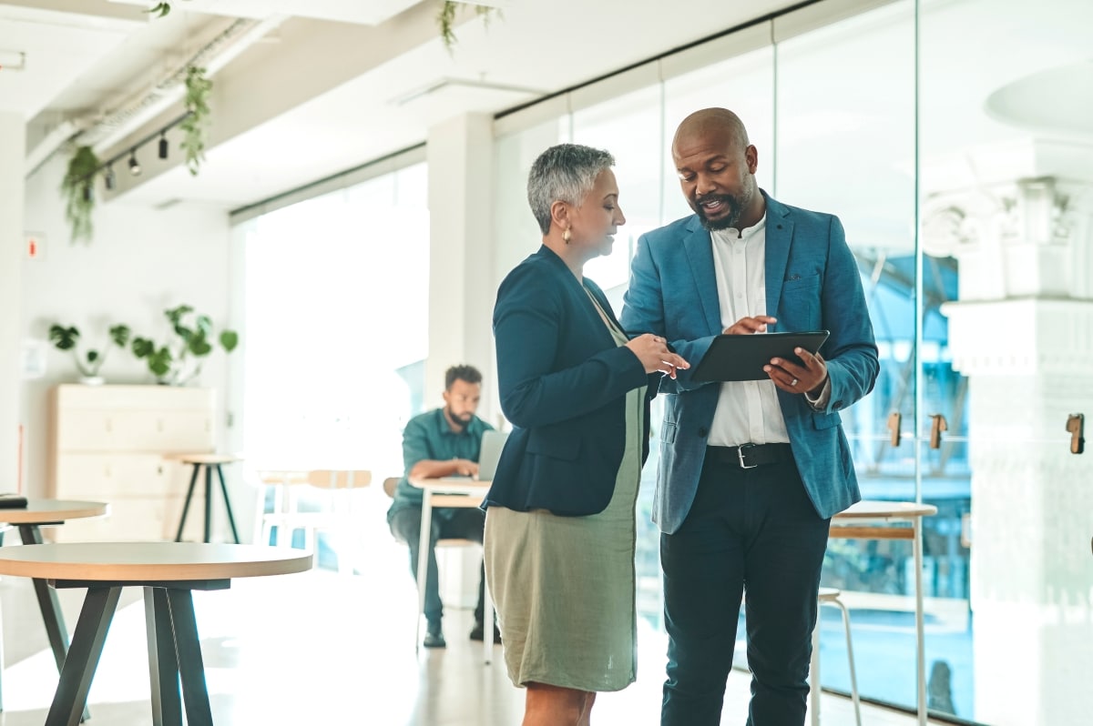 Zwei Business-Professionals besprechen einen strategischen Plan auf dem Tablet als Symbol für die ersten 90 Tage als neuer CFO.