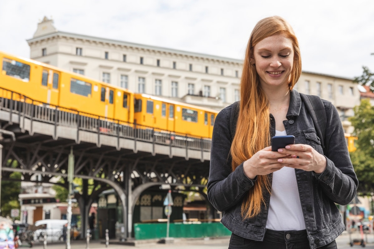 Eine junge Geschäftsreisende bedient ihr Smartphone.