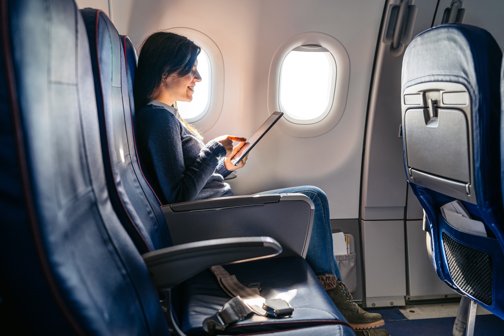 Frau im Flugzeug verwendet Concur Travel & Expense für ihre Geschäftsreise