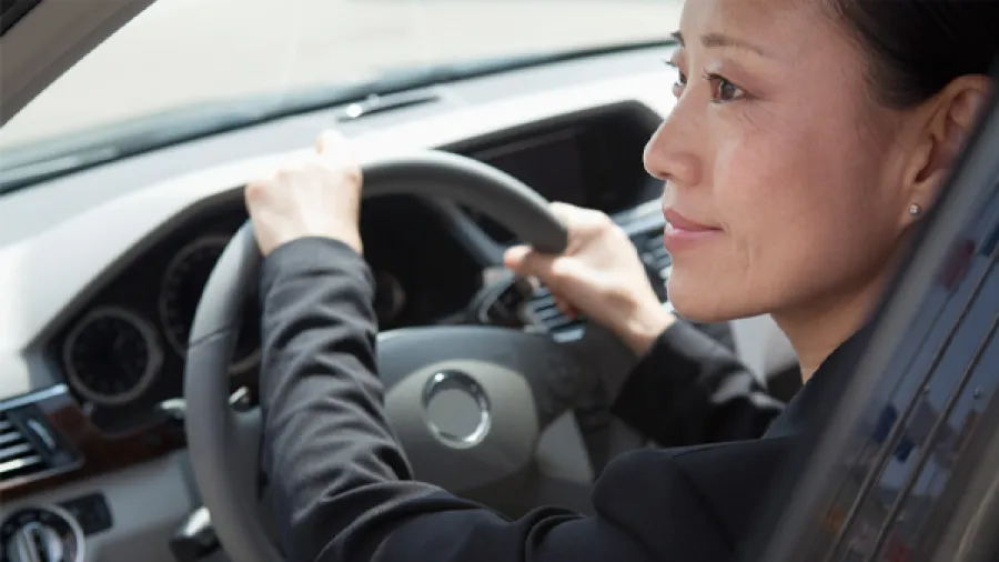 Eine Geschäftsfrau fährt ein Auto und nutzt die automatische Kilometererfassung.