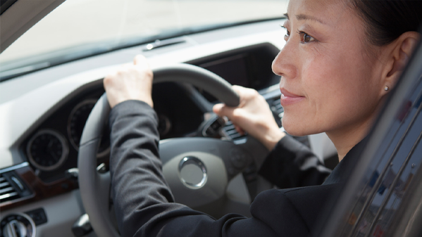 Eine Geschäftsfrau fährt ein Auto und nutzt die automatische Kilometererfassung.