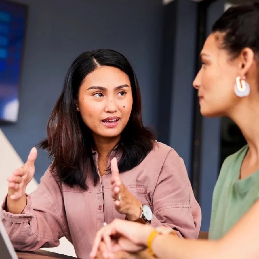 Eine Mitarbeiterin erklärt im Büro die Funktionen der SAP Concur Software auf dem Bildschirm