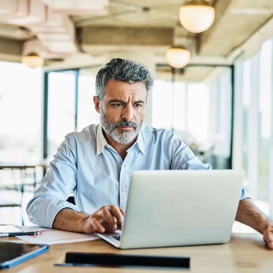 Mitarbeiter sitzt mit Laptop in einem modernen Büro und prüft digitale Ausgaben.