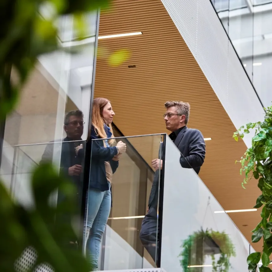 Mann und Frau stehen in einem modernen Bürokomplex.