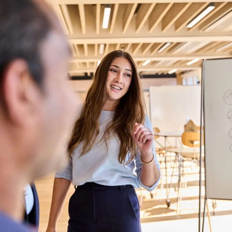 Eine Mitarbeiterin erklärt im Büro die Funktionen der SAP Concur Software auf dem Bildschirm