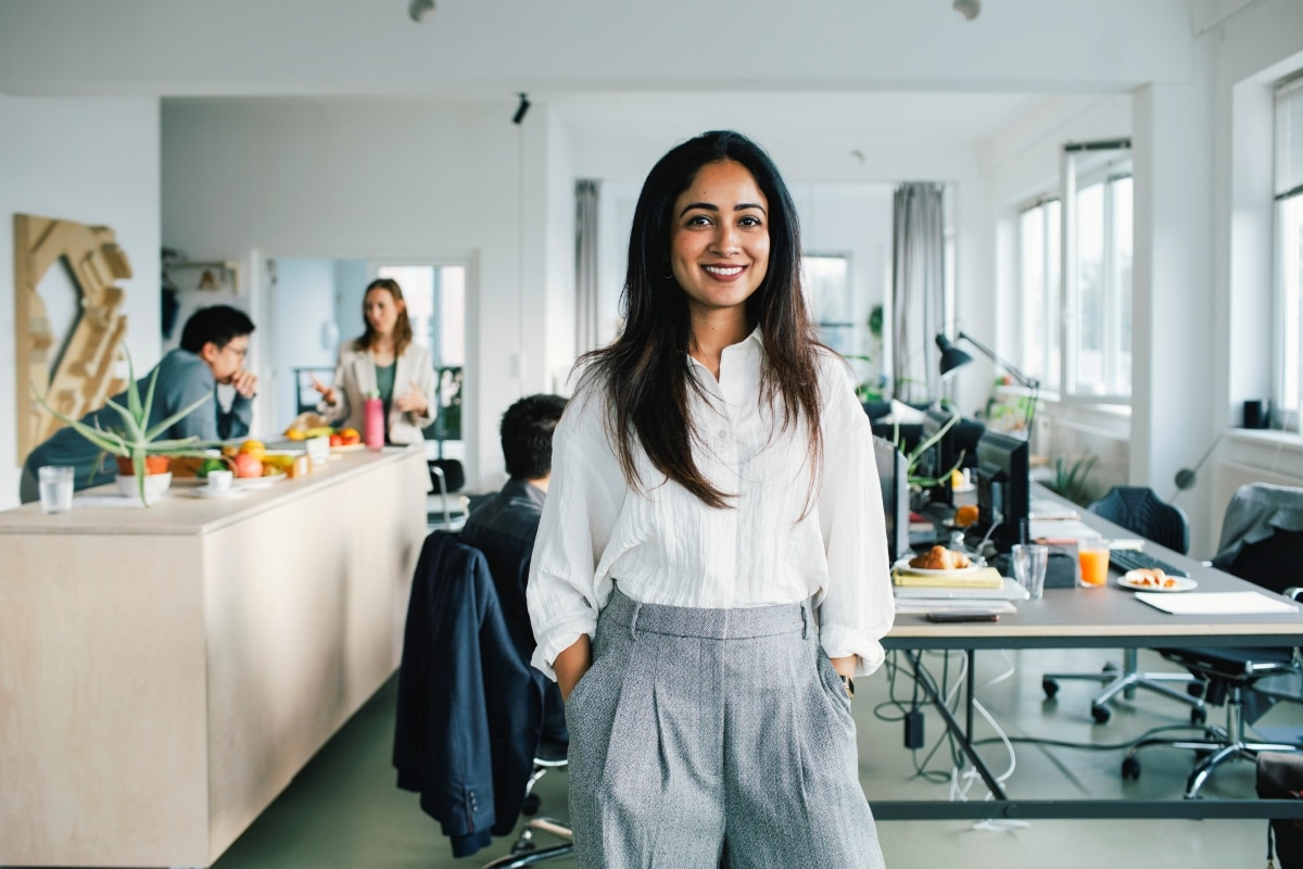 Business-Frau freut sich über den Leitfaden von SAP Concur zu den Anforderungen an globales Reisekostenmanagement.
