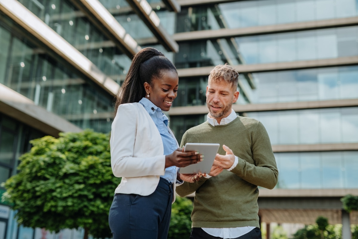 Frau und Mann schauen sich am Tablet das E-Book von SAP Concur und Accenture zum Thema Compliance-Anforderungen an.